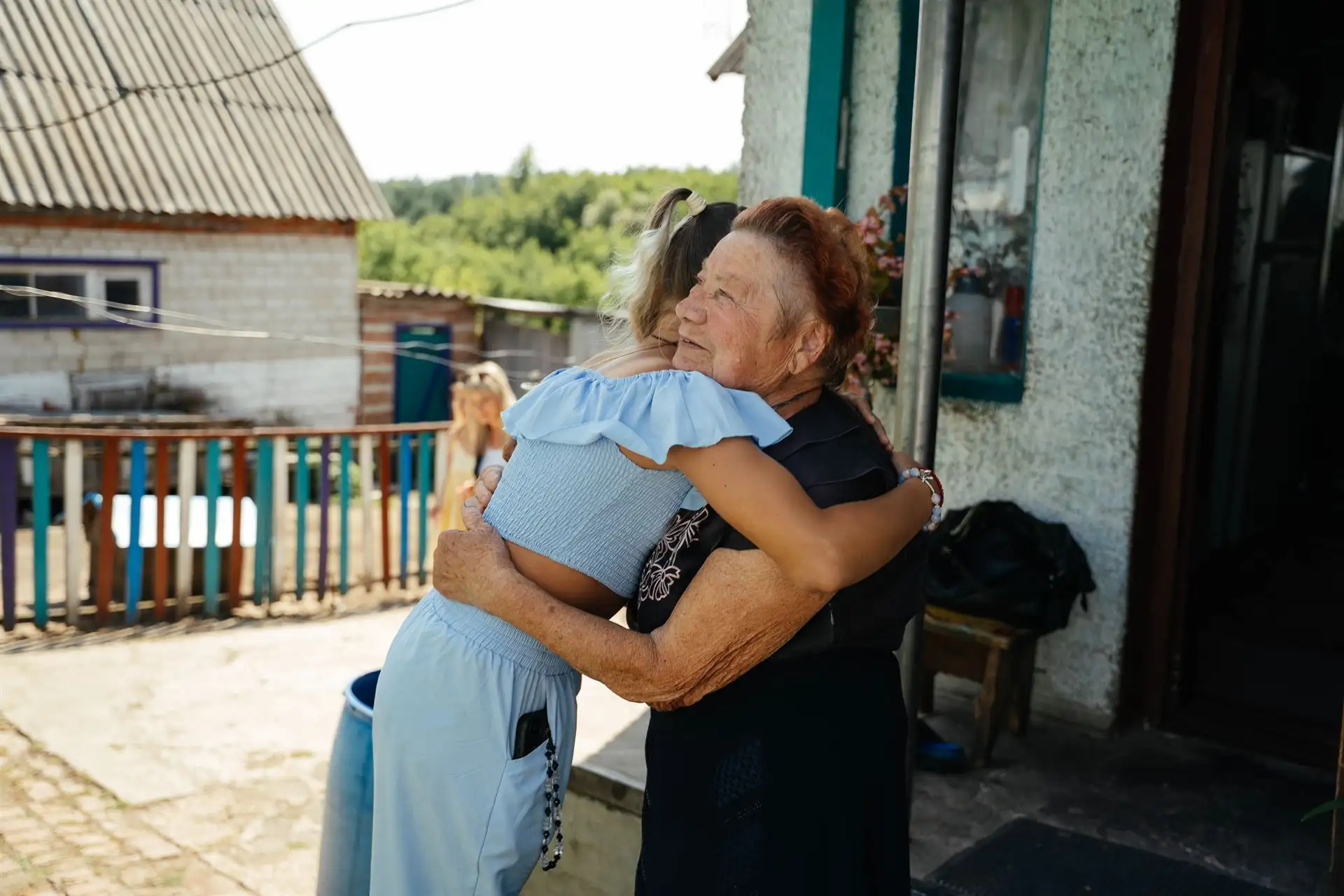Бабуся обіймає онучку в селі