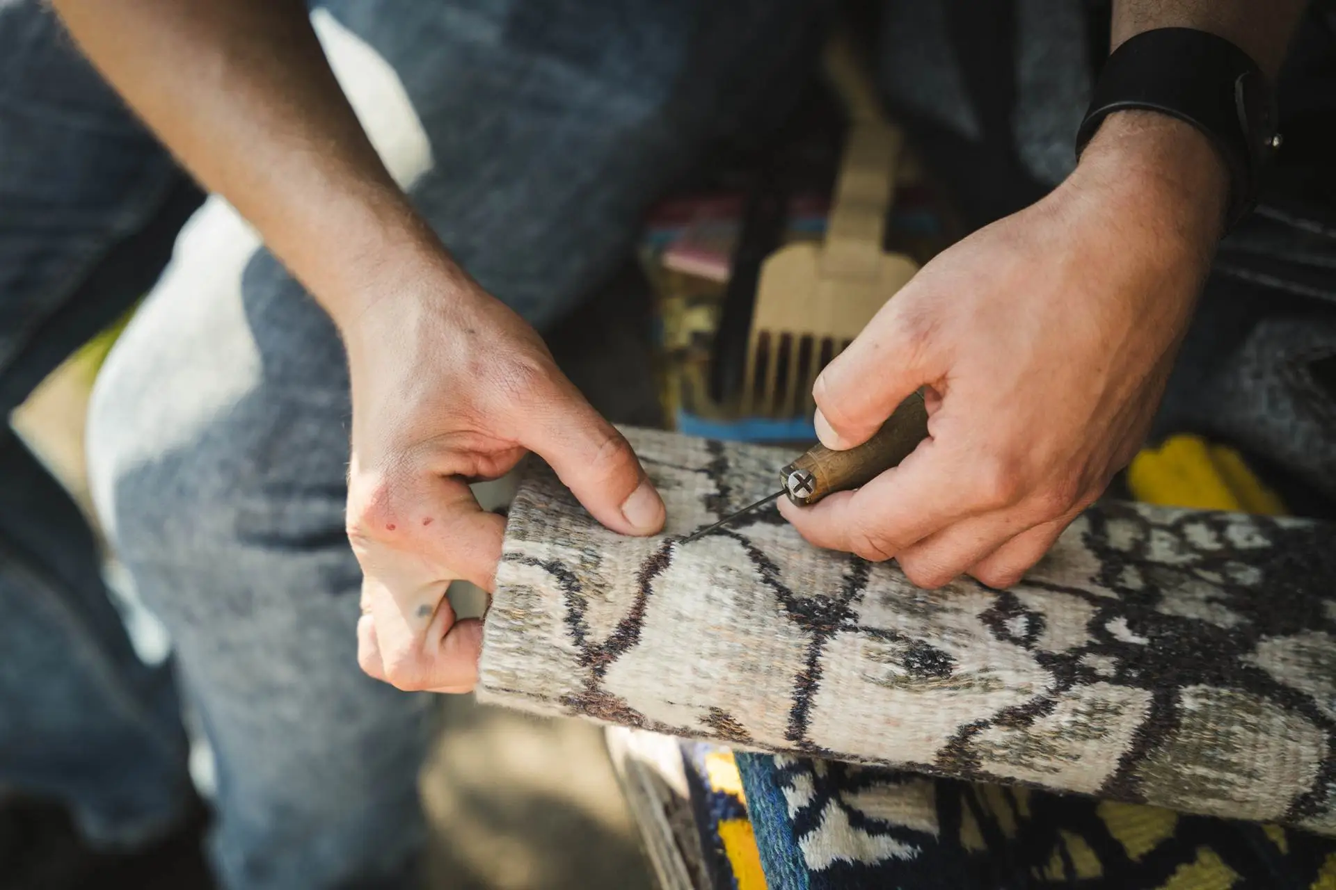 Ткач з'єднує нитки гобелена за допомогою крючка