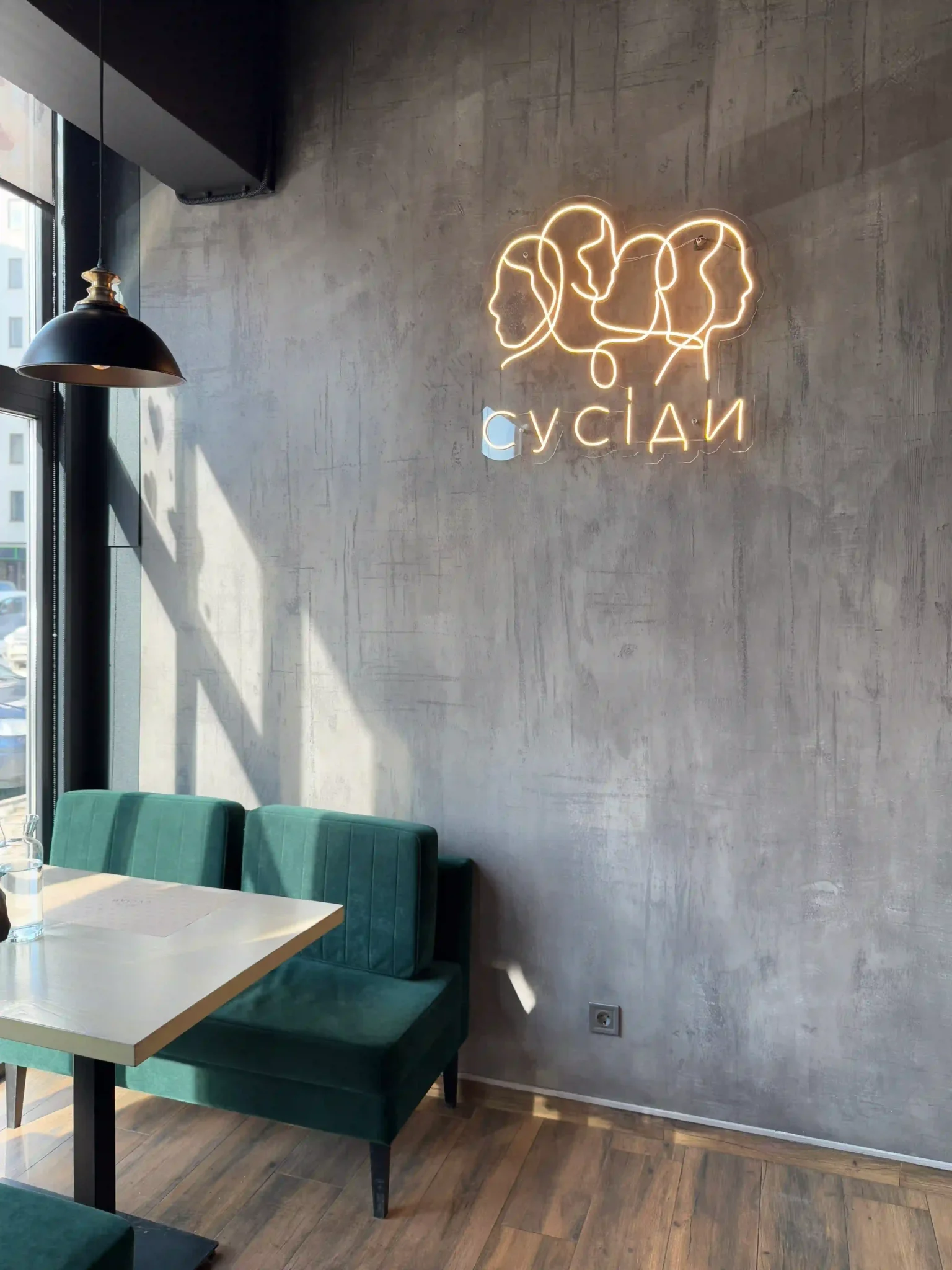 interier kaviiarni Усередині кав'ярні «Сусіди» простір доповнюють смарагдові крісла й неонові портрети.