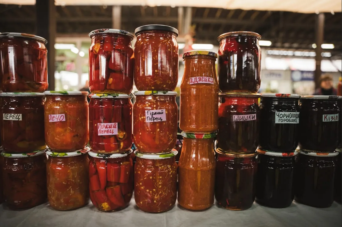 Банки джему й консервованих овочів, які продає Анна.