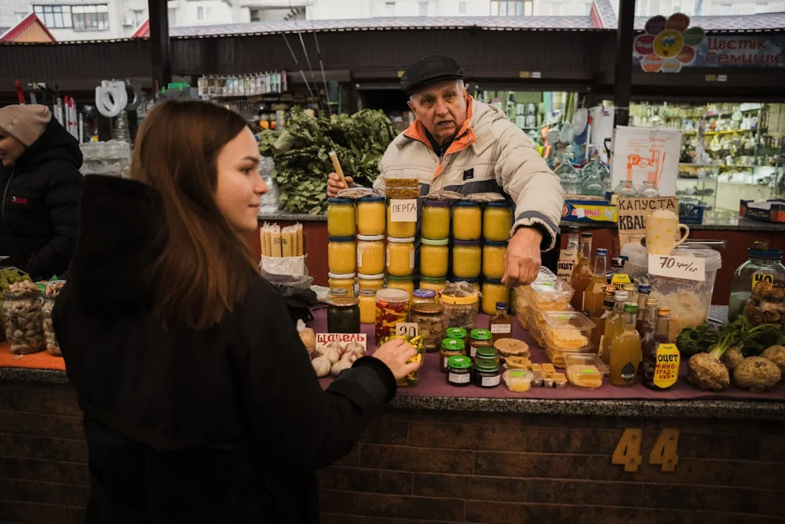Василь захоплено розповідає журналістам про свою пасіку й товари, які продає.