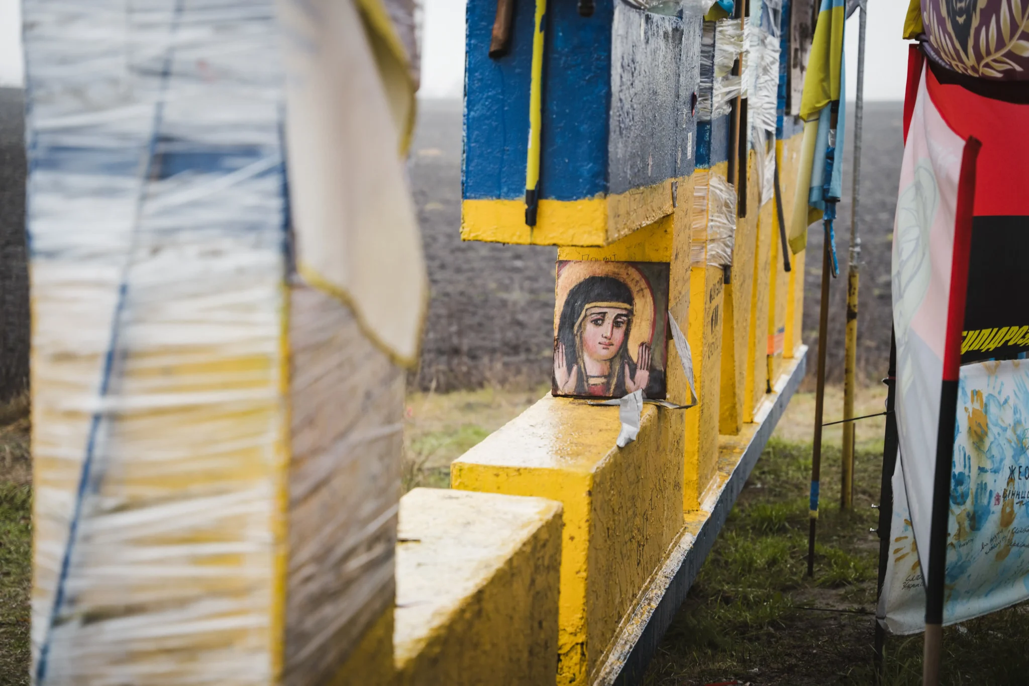 Всередині однієї з літер почепили ікону Божої Матері. Поряд з нею височіють прапори.