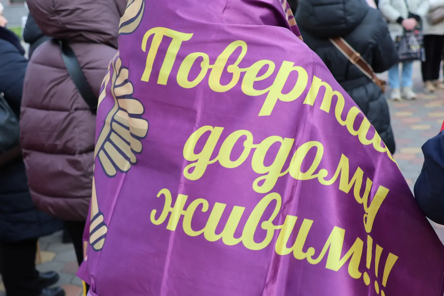 Людина з плакатом Повертайся додому живим 