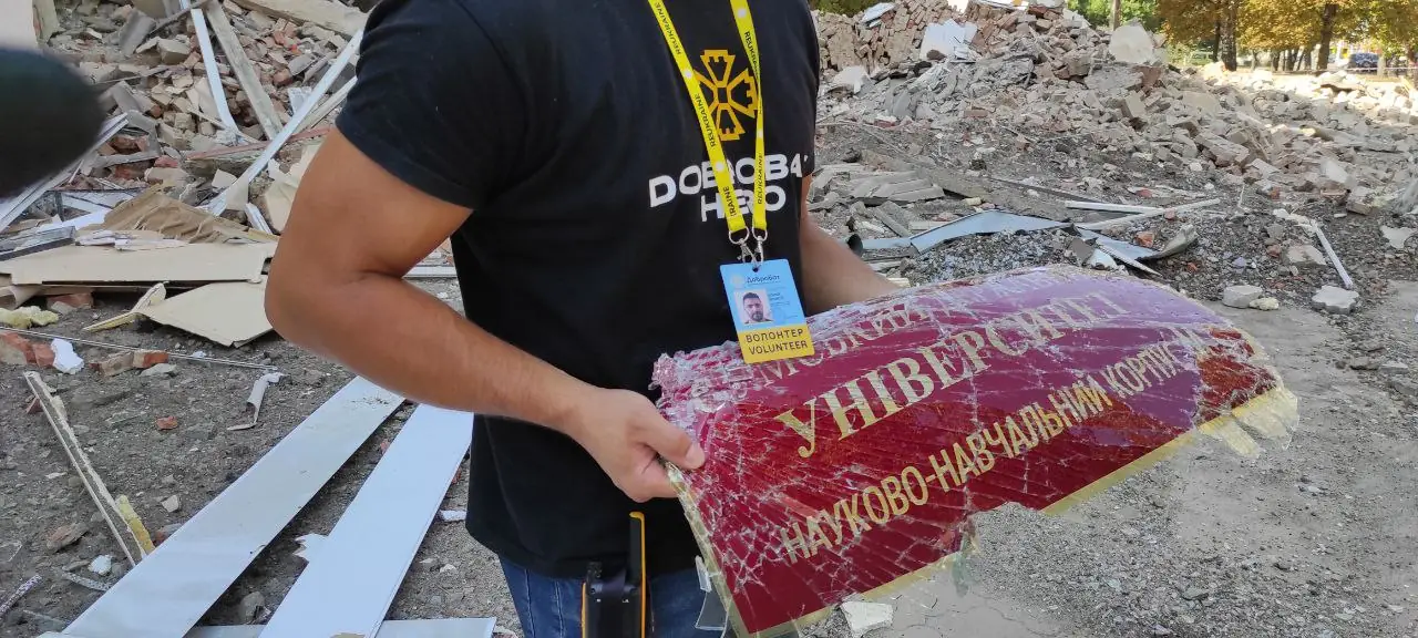 чоловік тримає в руках понівечену табличку з назвою