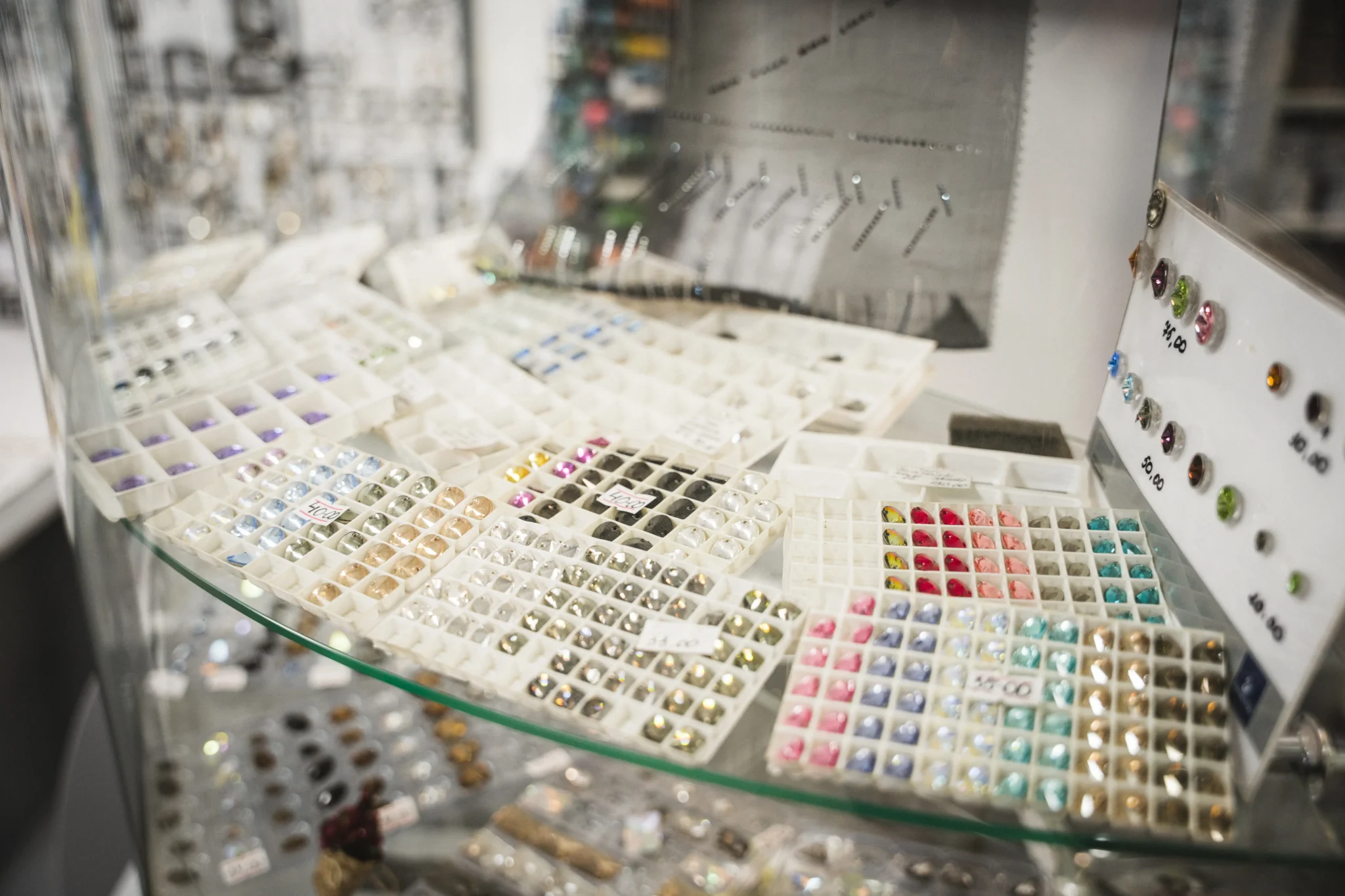 Контейнери з різнокольоровими камінцями блищать під вітринним склом.