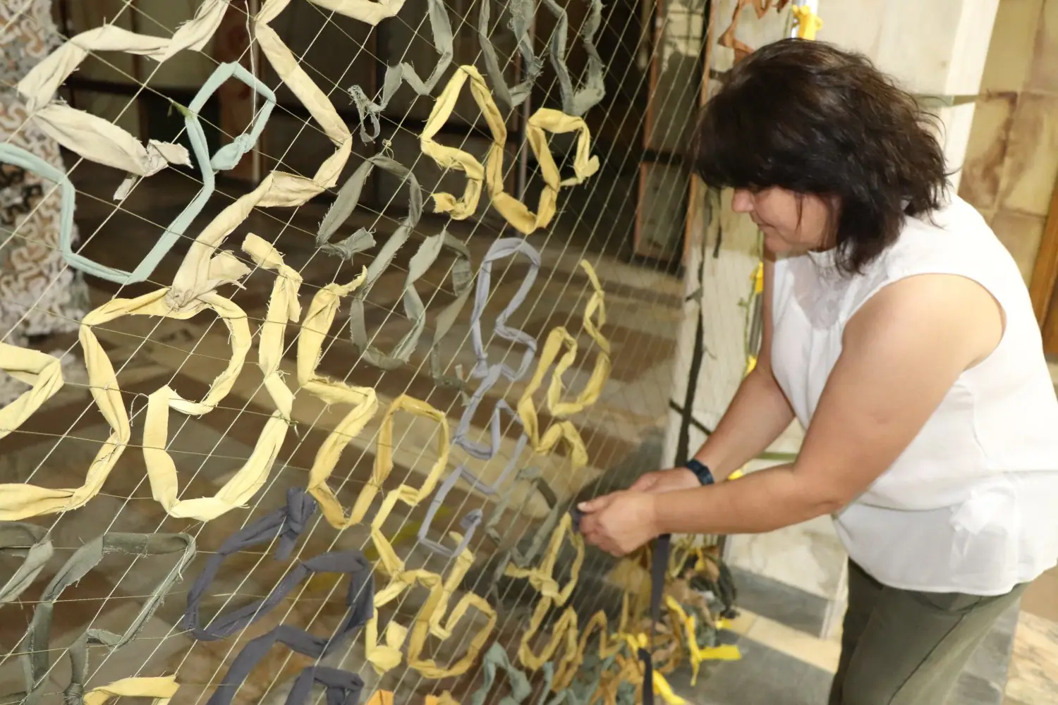 Жінка плете маскувальну сітку