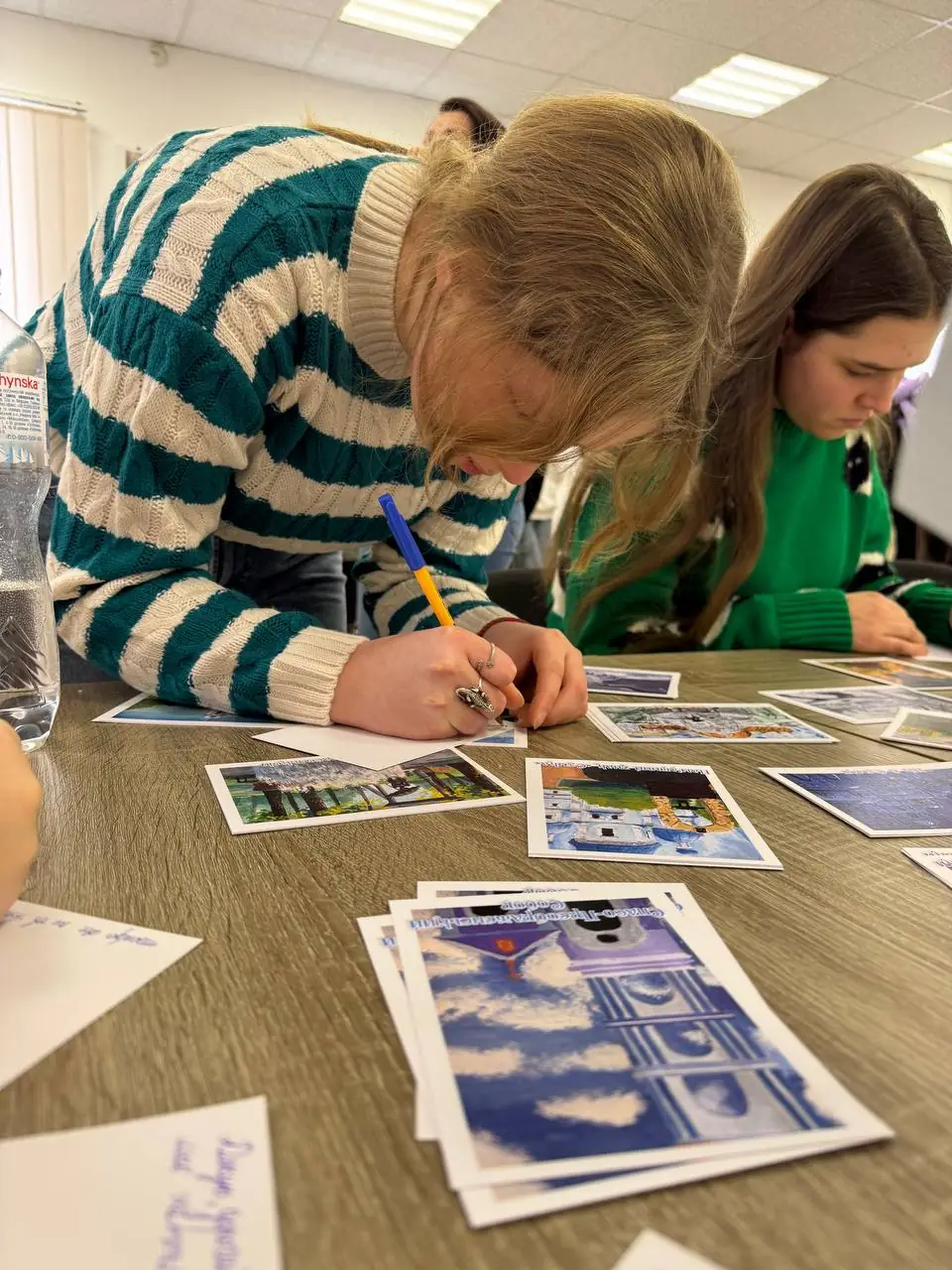 Дівчина підписує поштову листівку на фронт