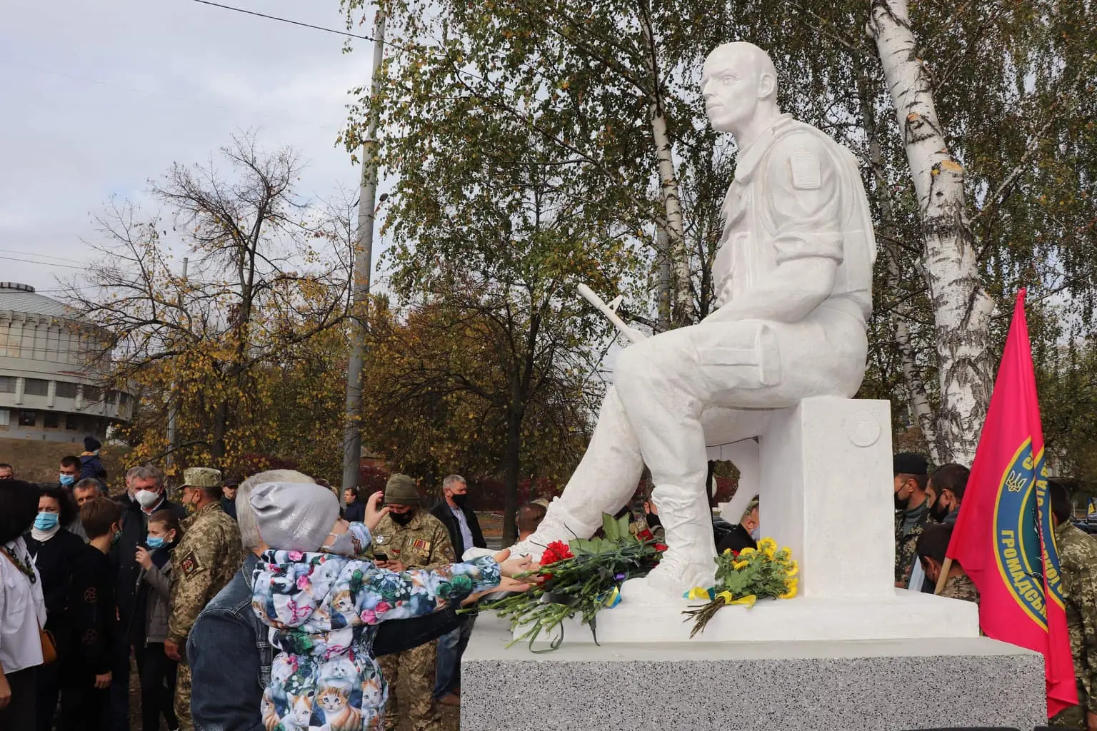 Люди вшановують воїнів АТО квітами. Вони кладуть їх на фундамент пам'ятника.*