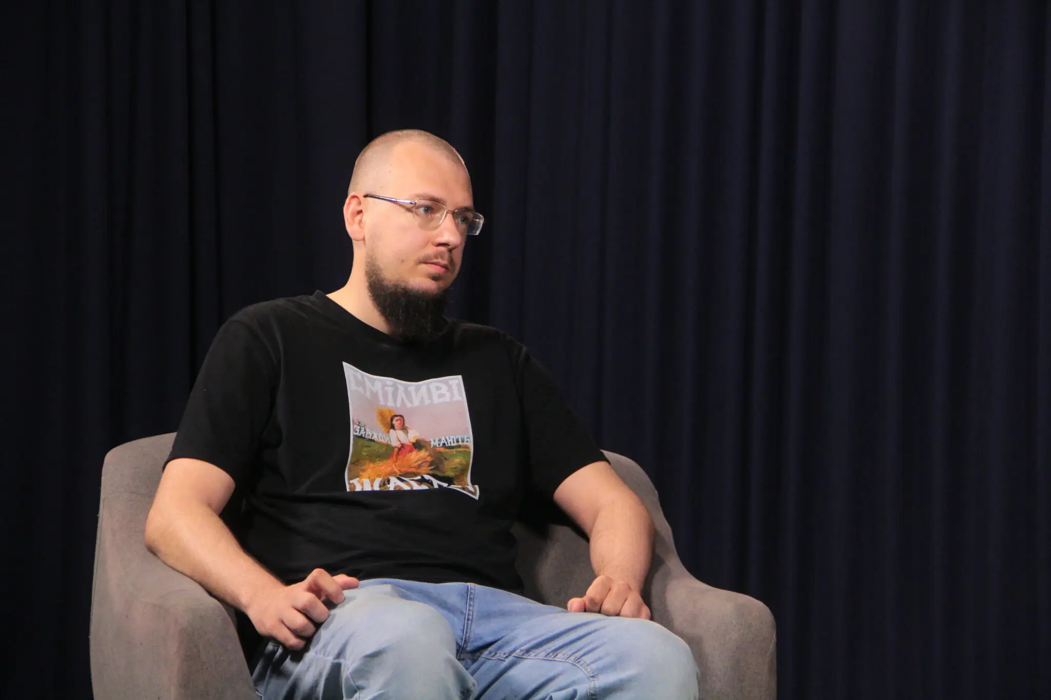 Вадим Поздняков дає інтерв'ю на кріслі. Позаду нього - чорні штори.