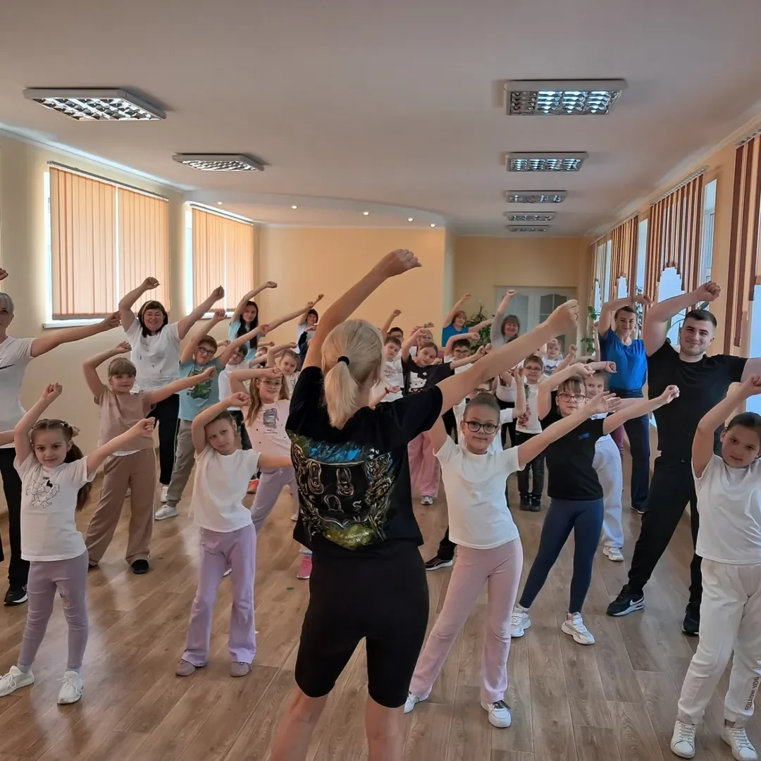 Вчителька на уроці фізкультури показує дітям вправи