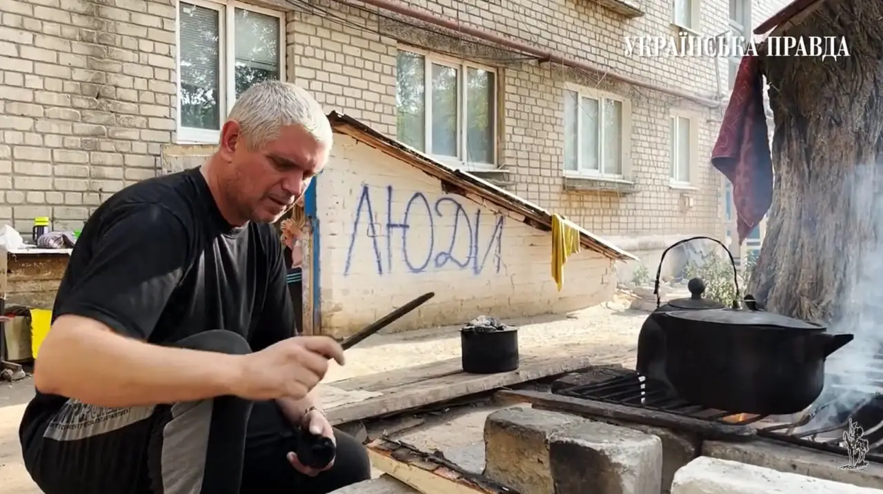 Чоловік у Сіверську готує їжу на подвір'ї.