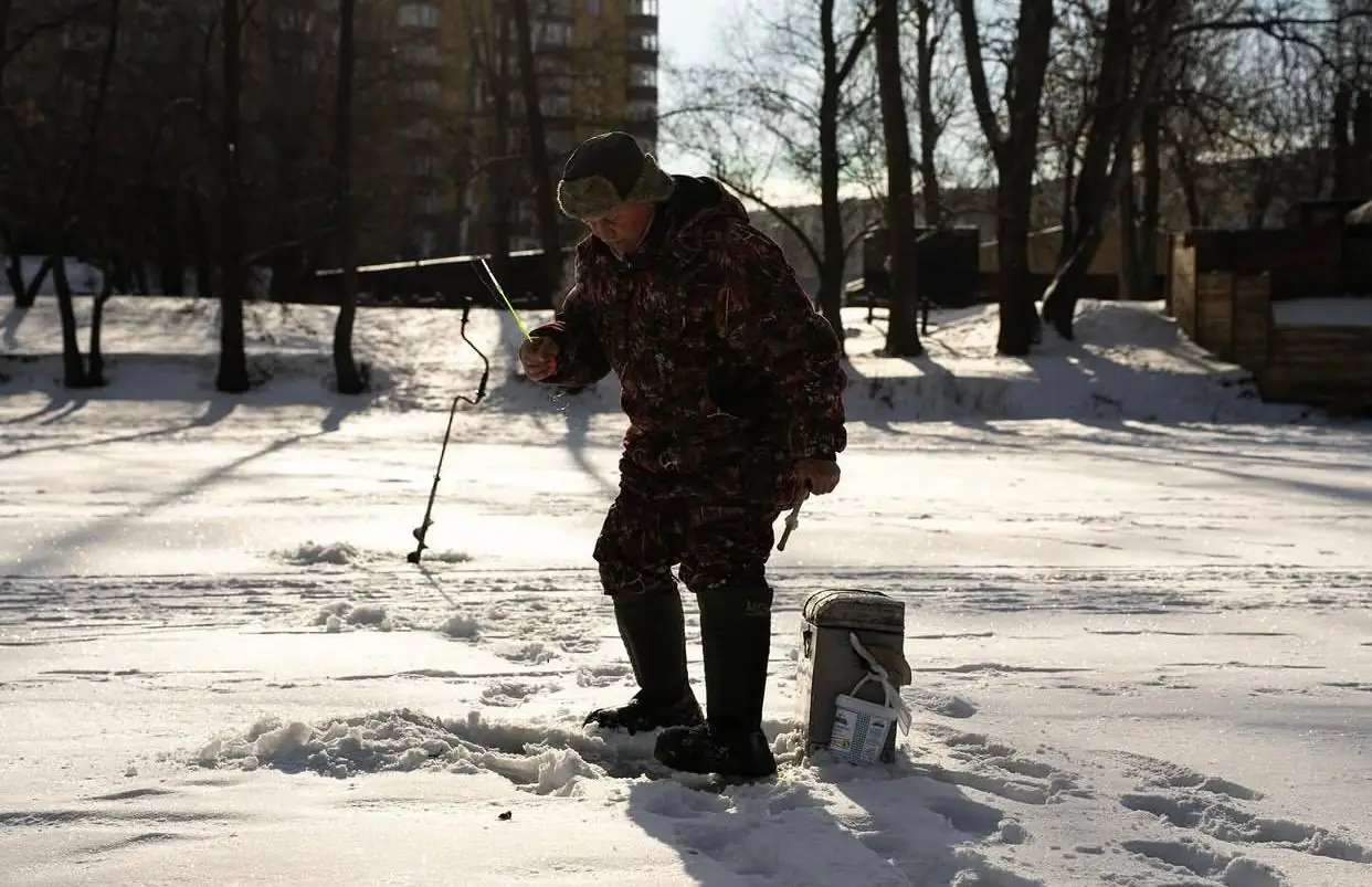Рибалка на Пслі стоїть і тримає в руках вудку.